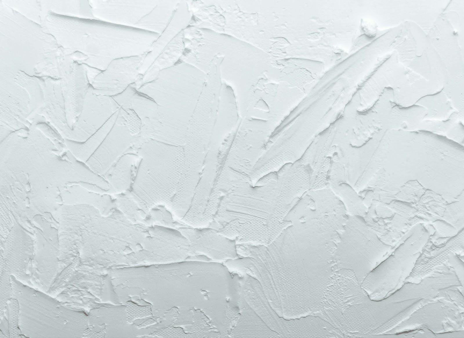 A white wall featuring colorful paint splatters, showing recent plaster repair work and artistic expression.