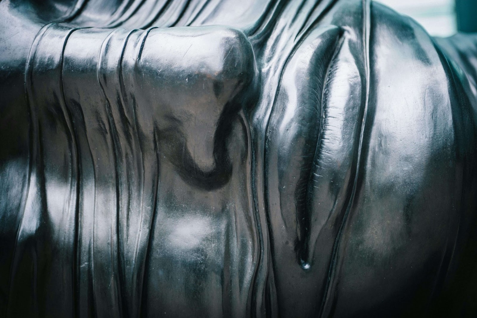A close-up of a statue featuring long black hair, showing intricate details and a striking metallic finish.