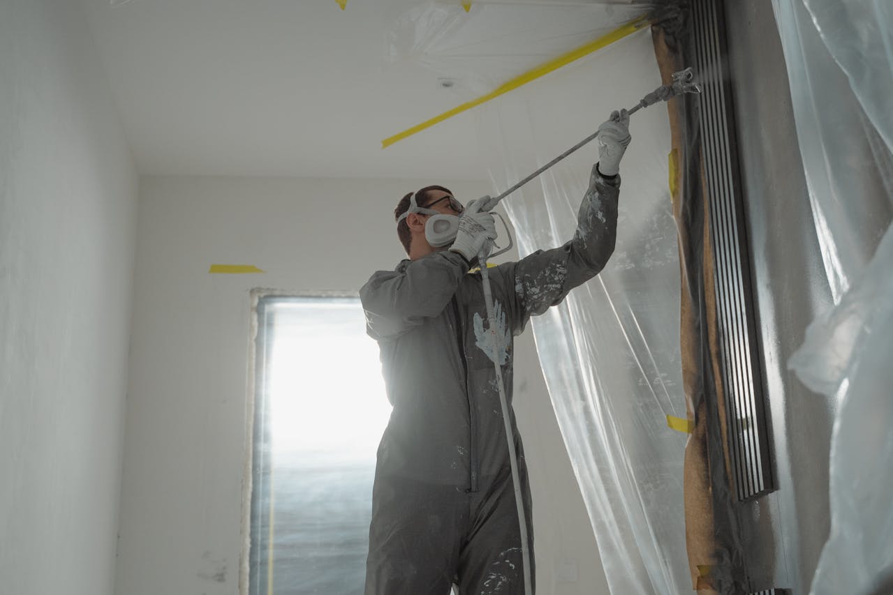 A man in a suit skillfully paints a room, representing professionalism in home improvement by Athena Best Painting Services.