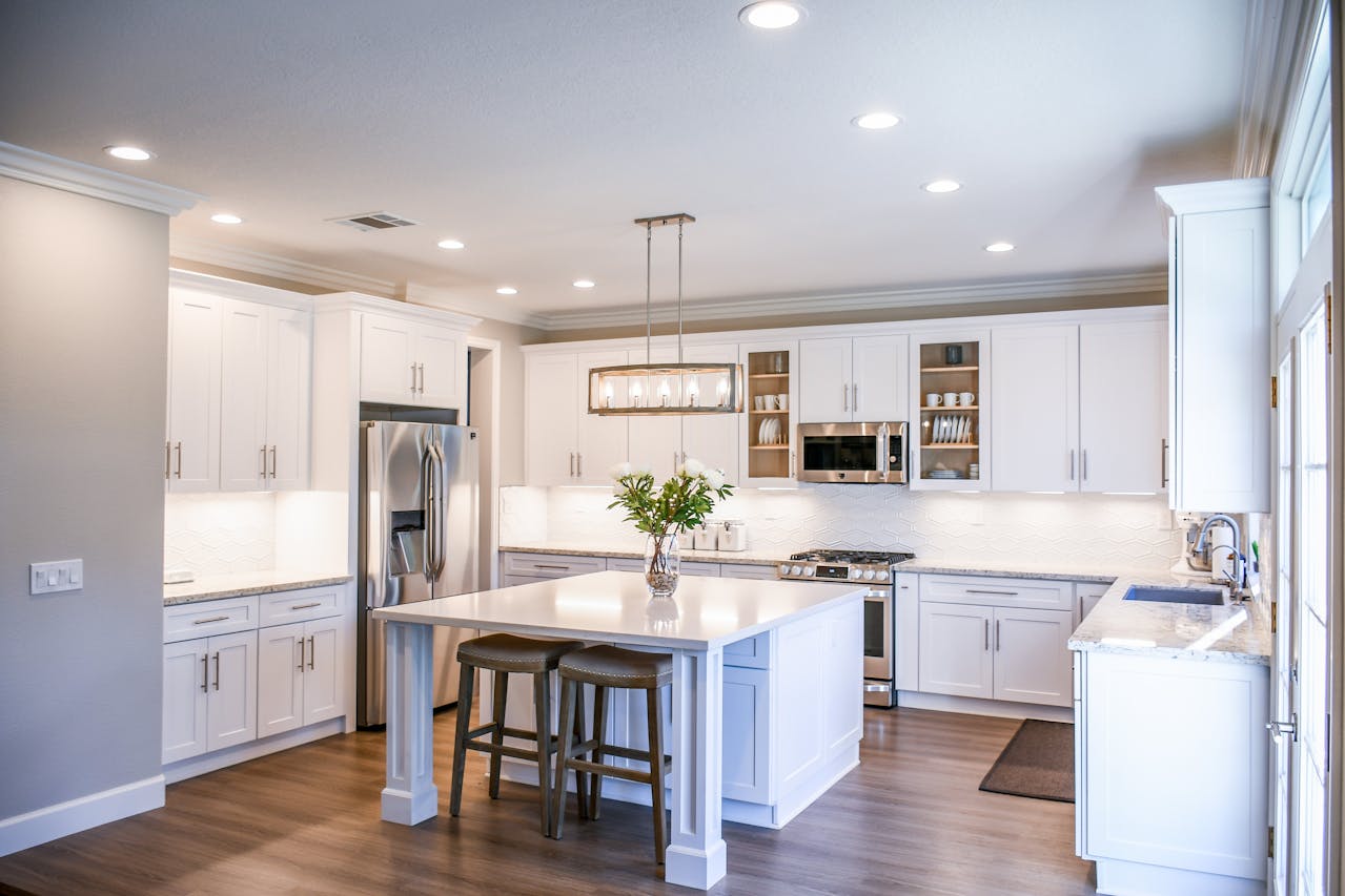 A pristine kitchen featuring white cabinets and a central island, showing the quality of Athena Best Painting Services.