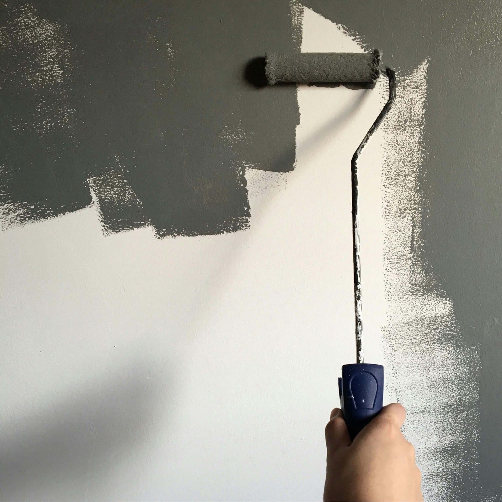 A person applies a metallic finish to a wall using a paint roller, showing bright colours and smooth application.