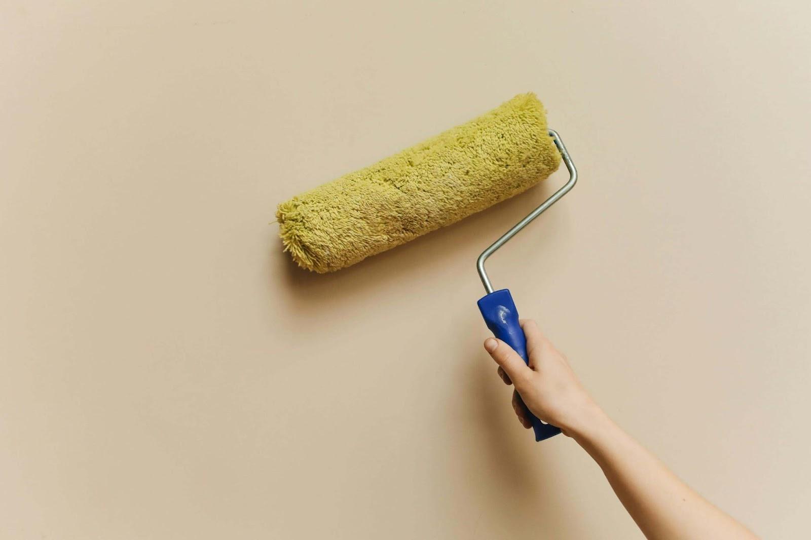 A professional painter using a paint roller to apply fresh paint on a wall, showing expert painting services.