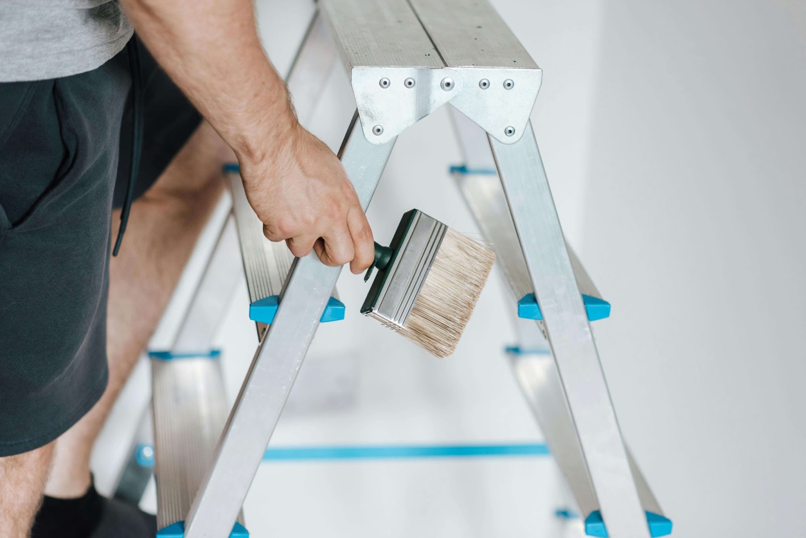 A man applies faux finishes to a ladder using a brush, showing his artistic skills in home improvement.