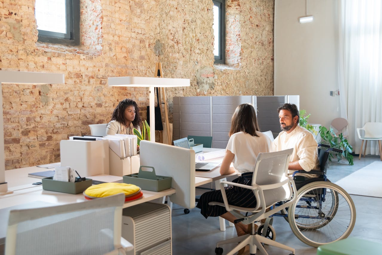 A diverse group of individuals in an office setting, including a person in a wheelchair, representing inclusivity at Athena Best Painting Services.