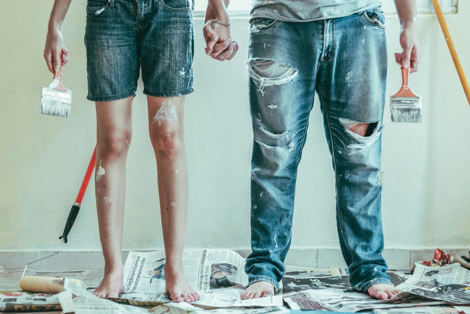 A man and woman stand in a paint shop, surrounded by paint brushes, showing Athena Best Painting Services.